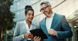 Man, woman and tablet for business in city with smile for approval, deal or notification from contact. People, partner and digital touchscreen with reading, happy and app for good news